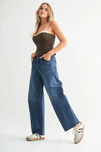 Woman wearing dark wash wide leg denim jeans with barrel seam and beige strapless top