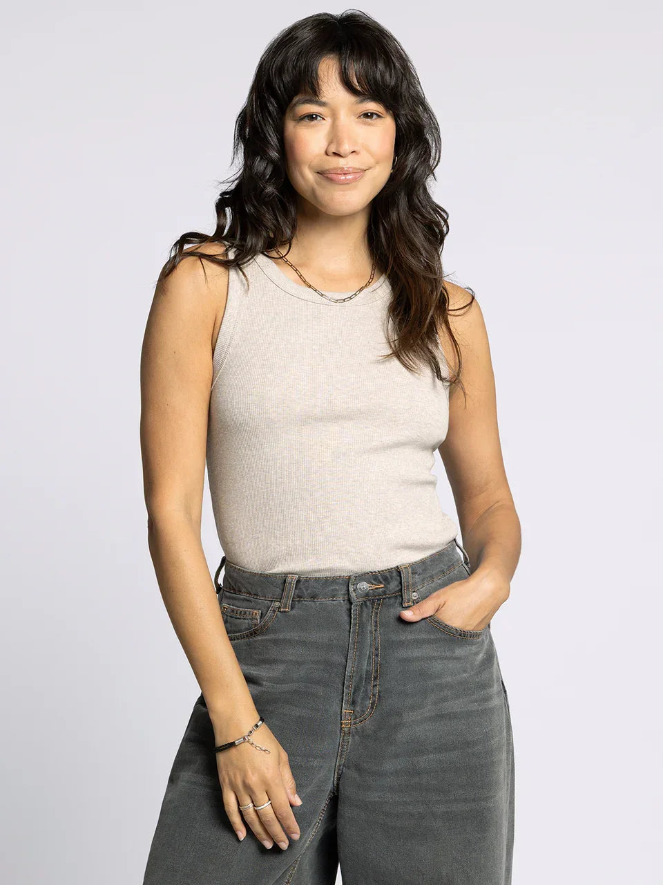 Woman wearing Edlin Basic Tank with dark wavy hair and dark grey wide-leg jeans
