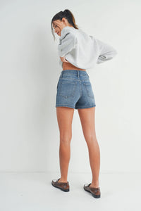 Woman in denim shorts and white cropped top, embracing a boho free spirit style