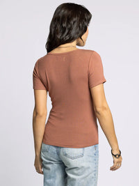 Woman wearing a supply katara tee with light wash blue jeans, stylish rust-colored shirt