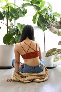 A woman sitting on the floor with a Padded Crochet Lace Longline Bralette and plant