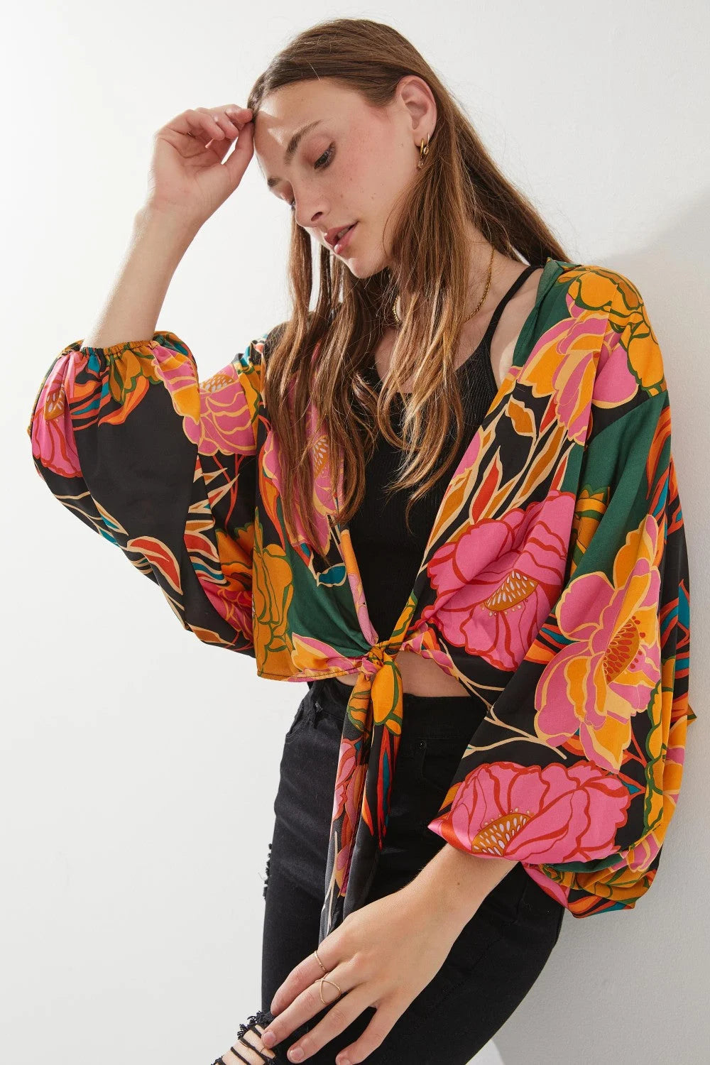 Woman in a floral print blouse featuring a stylish floral print tie-front cardigan