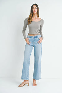 Woman in gray crop top and light blue jeans showcasing MID RISE SLIM WIDE LEG style