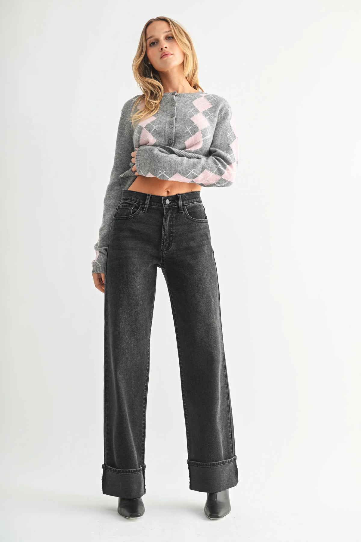 Woman wearing high rise cuffed wide leg jeans with gray argyle cardigan and black boots