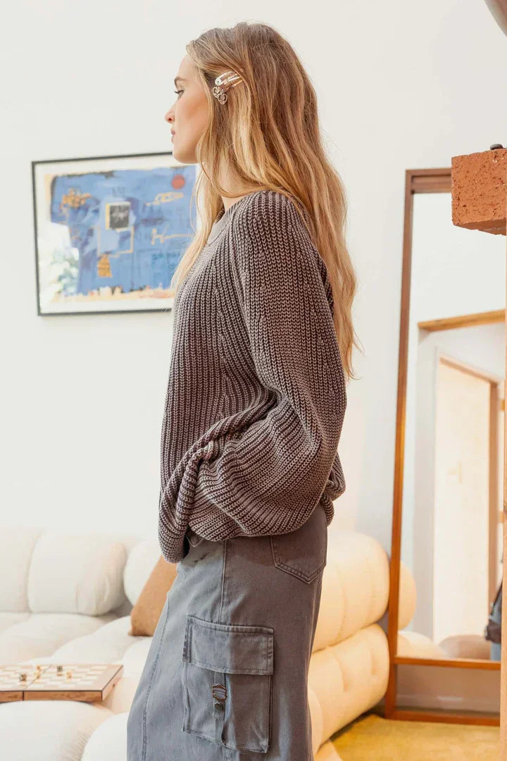 Woman in a gray knit pullover sweater and cargo pants posed in profile