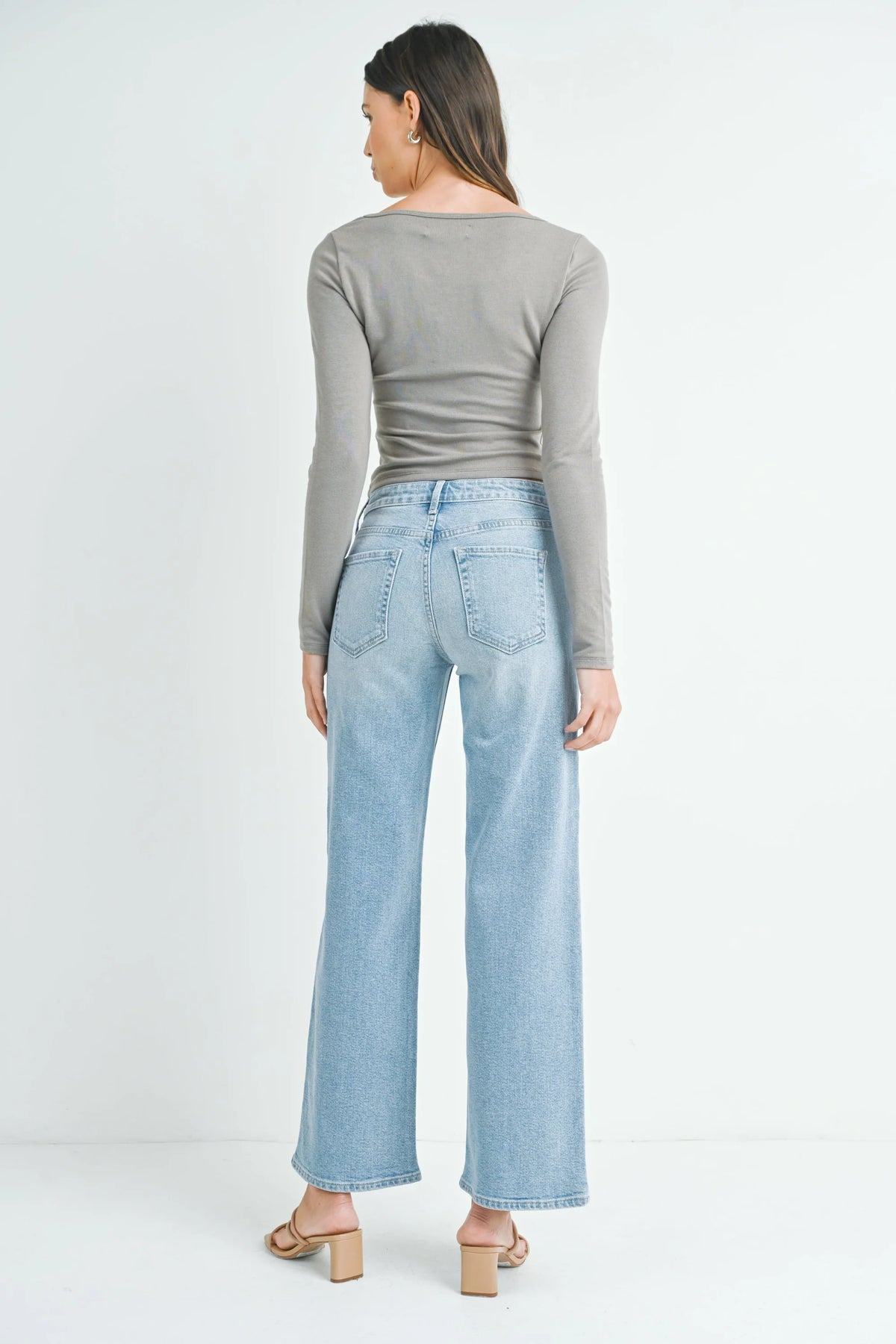 Woman in gray long-sleeved top and light blue wide leg jeans showcasing slim wide leg style