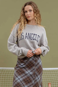 Woman in gray Los Angeles Knit Crewneck Pullover with a plaid skirt