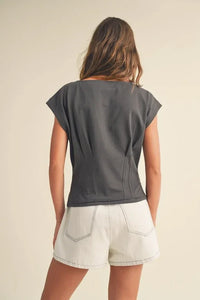 Woman in gray corset style body top and white shorts, viewed from behind