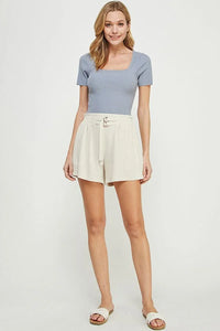 Woman in gray top and white soft linen blend shorts with double buckle detail