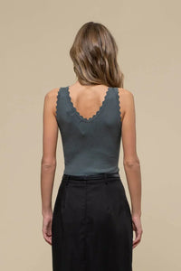 Woman in a gray scallop edge sleeveless top and black skirt, seen from behind