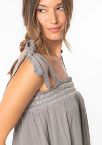Woman wearing a bohemian tie shoulder smocked tank top with tie-shoulder straps