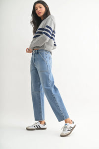 Woman in a gray striped sweater and blue jeans featuring utility seamed barrel design