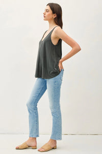 Woman in gray flowy V-neck tank top and light blue jeans, embodying a free spirit