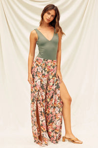 Woman in a green tank top and floral maxi skirt showcasing a double plunging bodysuit