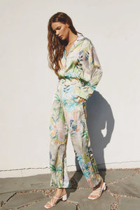 A woman models a flowy green and white floral print jumpsuit from OUT OF OFFICE SHIRT AND PANTS SET