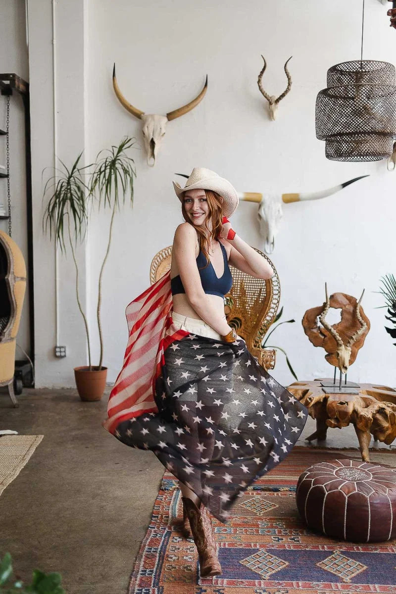 Woman in a hat and dress sitting on a rug showcasing lace racerback bralette