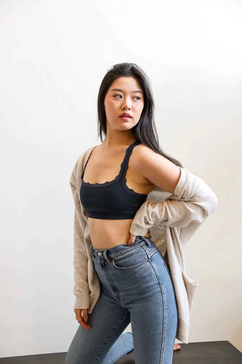 Woman in jeans and a black top showcasing the seamless lace strap bralette features