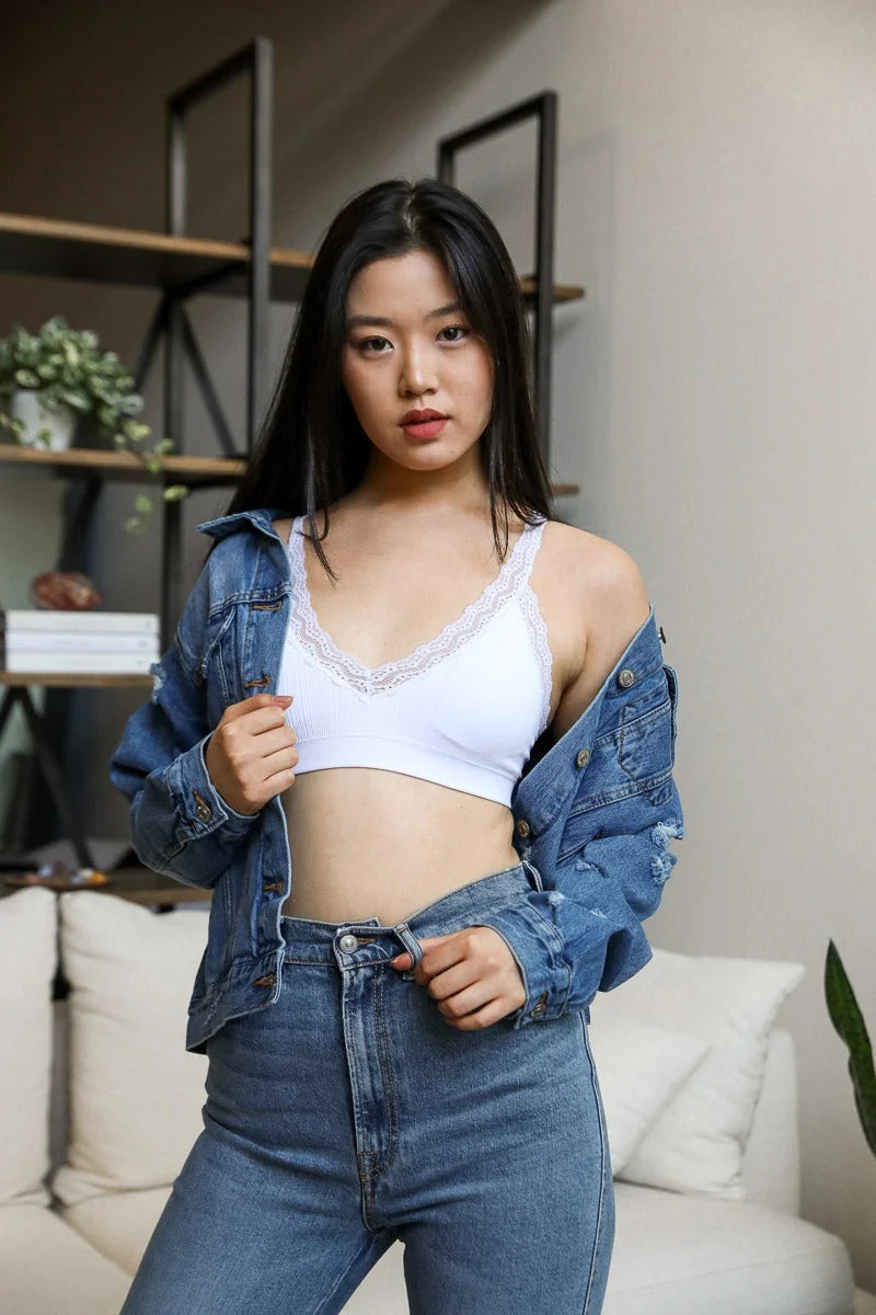 Woman in jeans and white top showcasing Lace Trim Padded Bralette, embodying feminine elegance