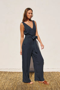 Woman in a navy blue BUTTON DOWN SASH BELT JUMPSUIT with v-neck button closures