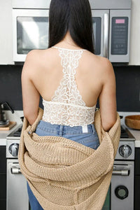 Woman in kitchen holding bag, showcasing Racerback Flower Lace Bralette Padded design