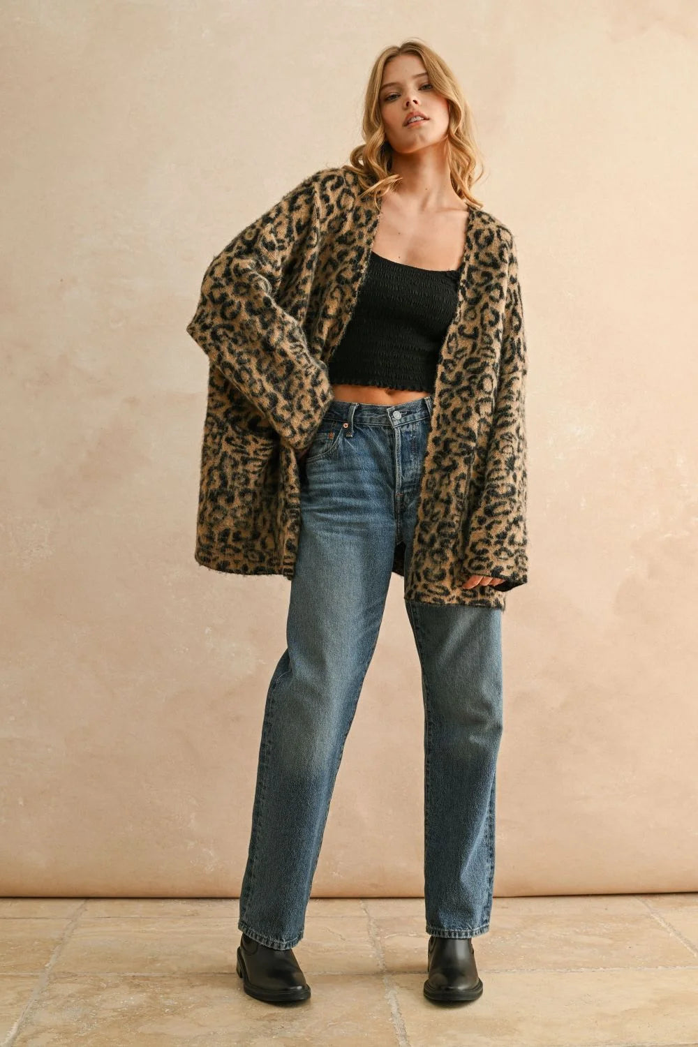 Woman wearing leopard oversized cardigan with black crop top and blue jeans