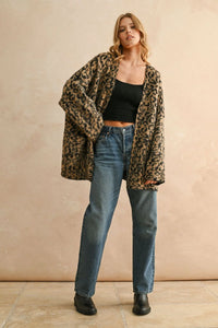 Woman wearing leopard oversized cardigan with black crop top and blue jeans