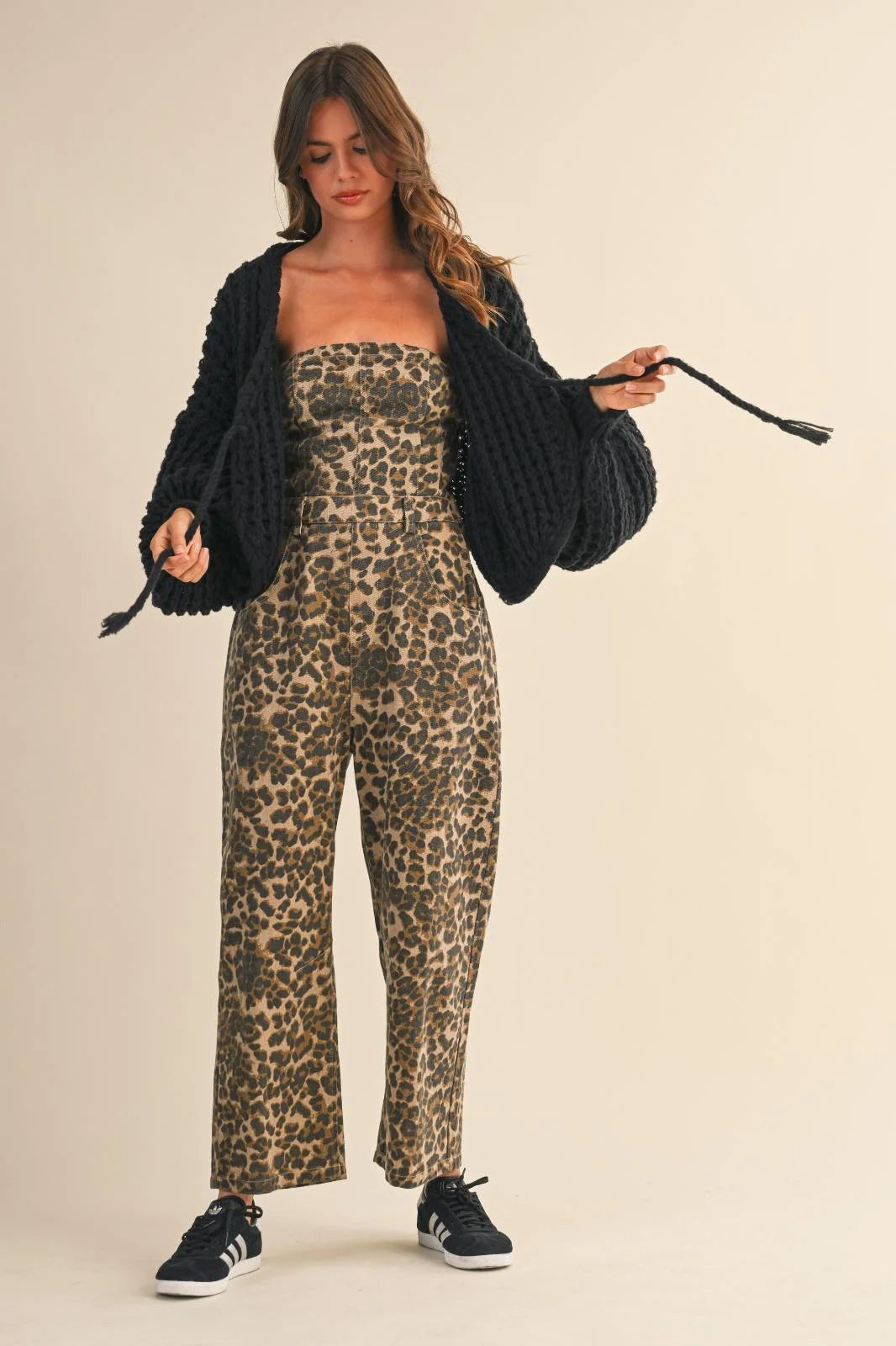 Woman wearing a stylish leopard print strapless barrel jumpsuit with a black open-front cardigan
