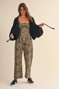 Woman wearing a stylish leopard print strapless barrel jumpsuit with a black open-front cardigan