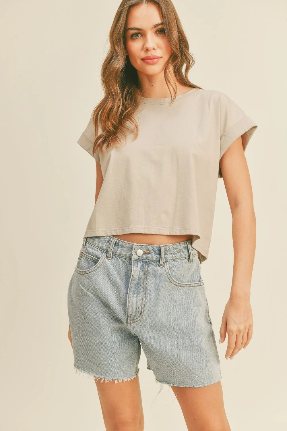 Woman wearing a round neck cuffed sleeve top with light-wash denim shorts