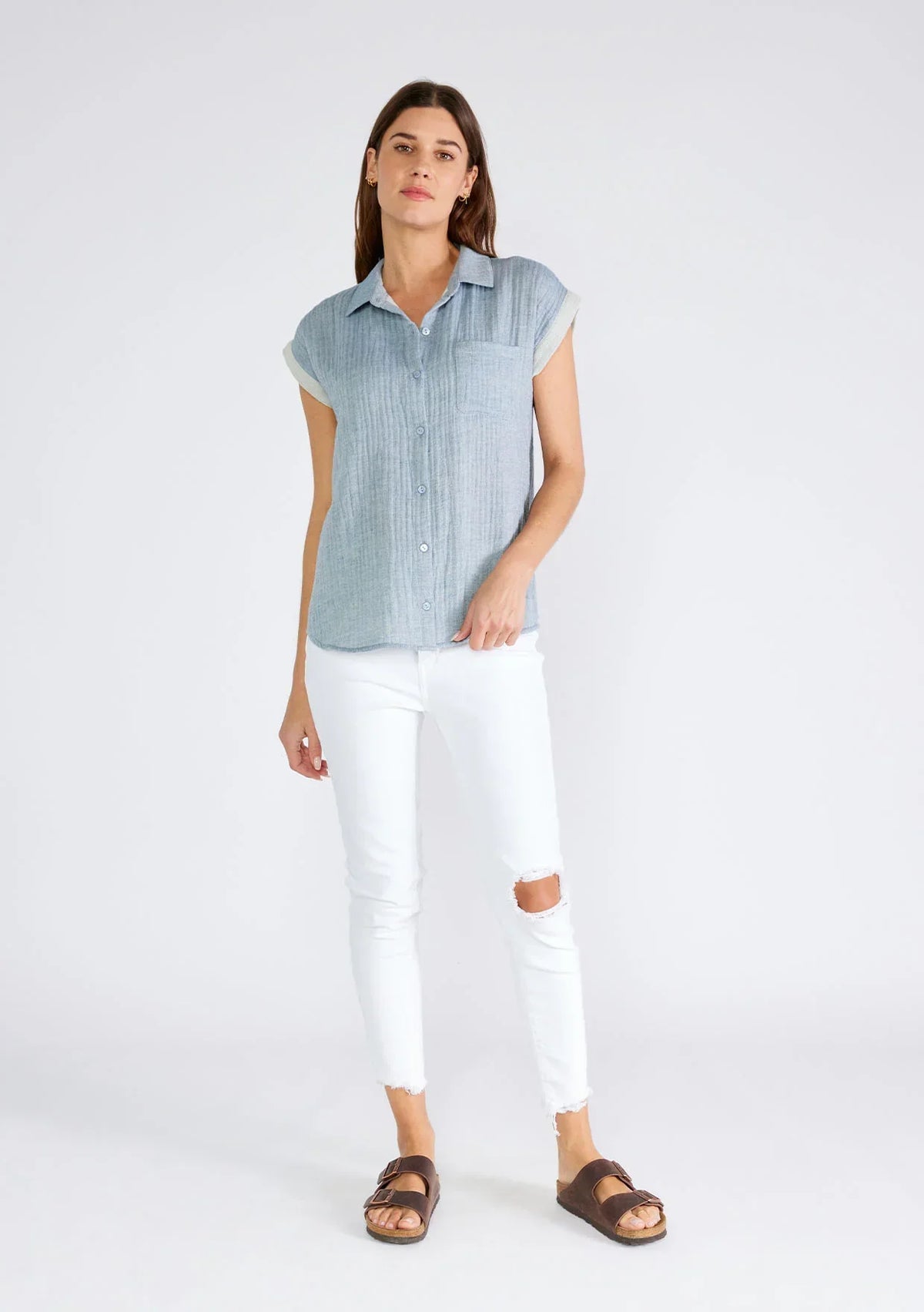 Woman in a flowy light blue Dolman Sleeve Button Front Top with white ripped jeans