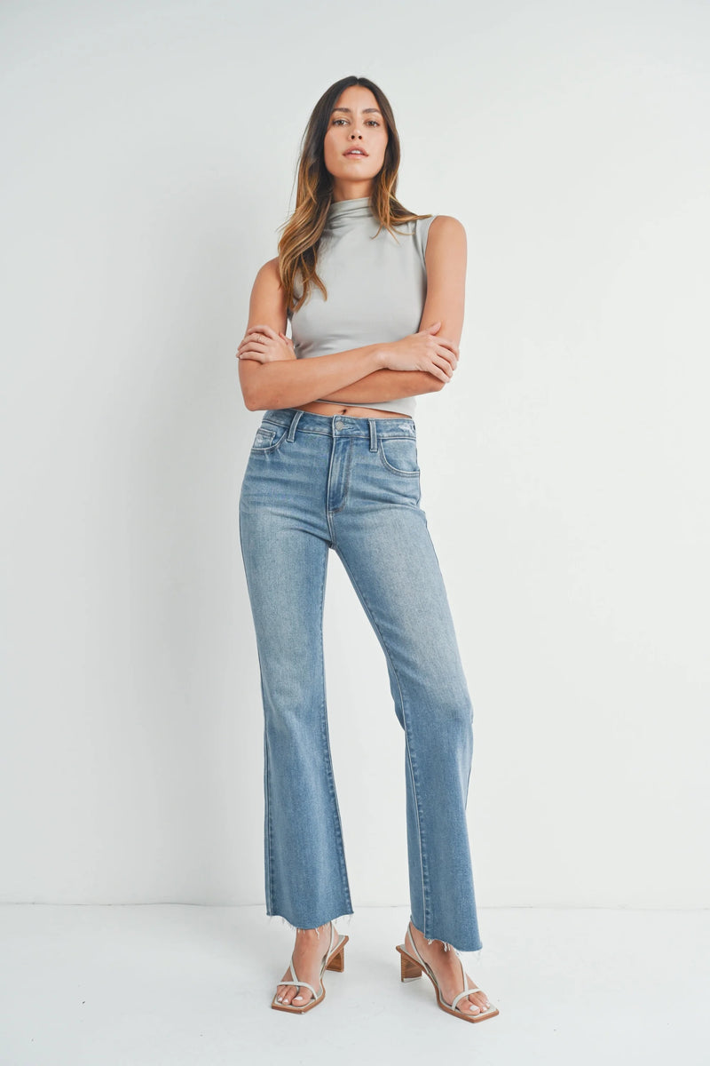 Woman in light blue flared jeans and gray top showcasing boho style with hem detail