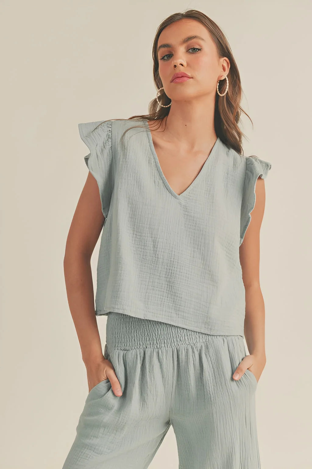 Woman in a light blue-green double gauze ruffled sleeve top with stylish shoulders