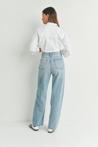 Woman in light blue high waisted skater jean and cropped white shirt from behind