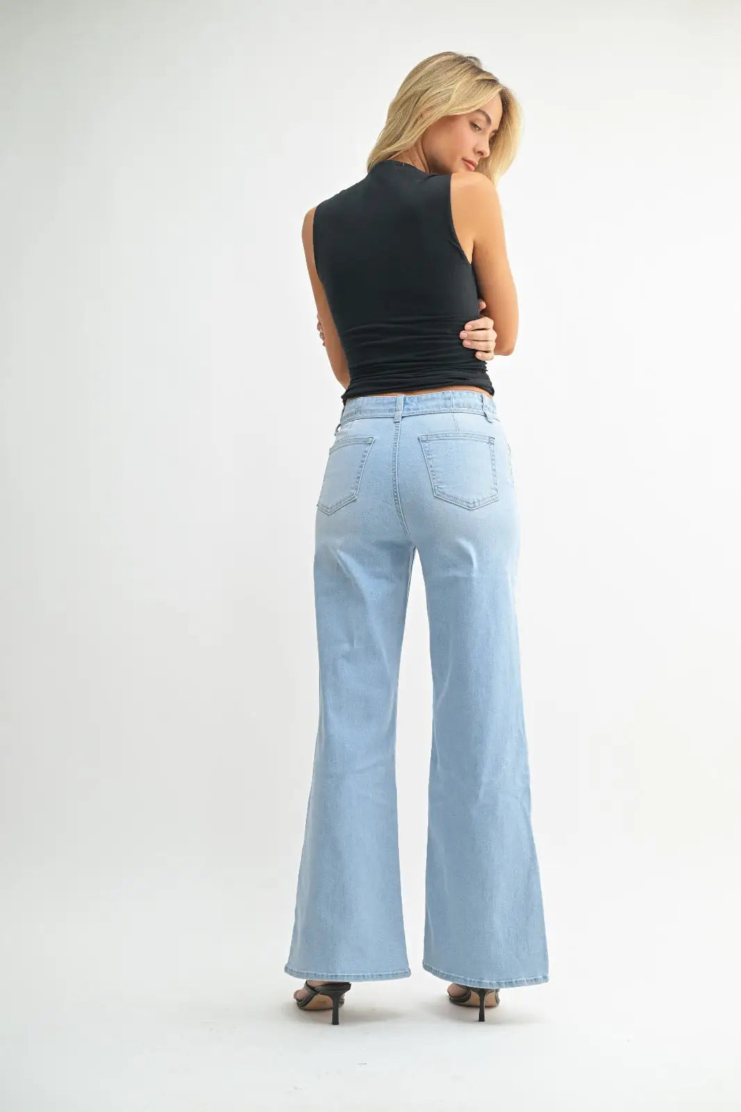 Woman showcasing light blue flared jeans from JUST BLACK DARK DENIM BELTED WIDE LEG