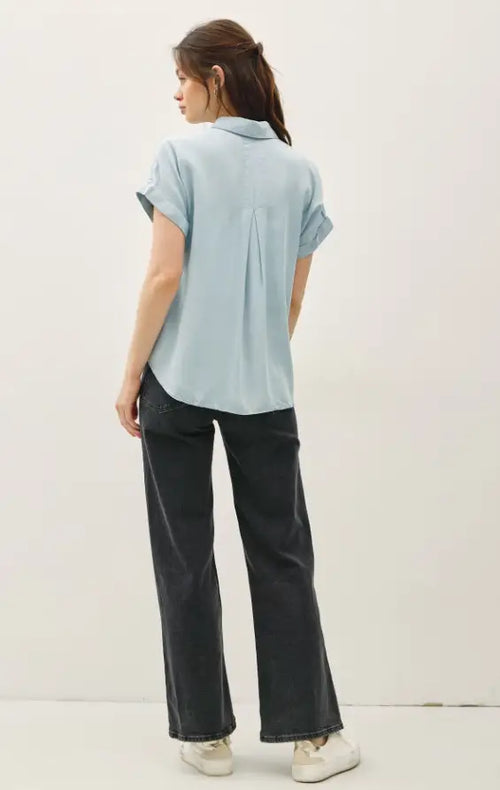Woman wearing light blue short sleeve pocket button down shirt from Shop Daisy Lane