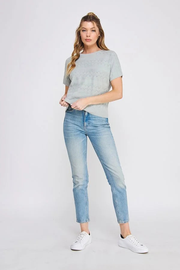 Woman in light blue jeans wearing a short sleeve patterned fine gauge knit dolman top