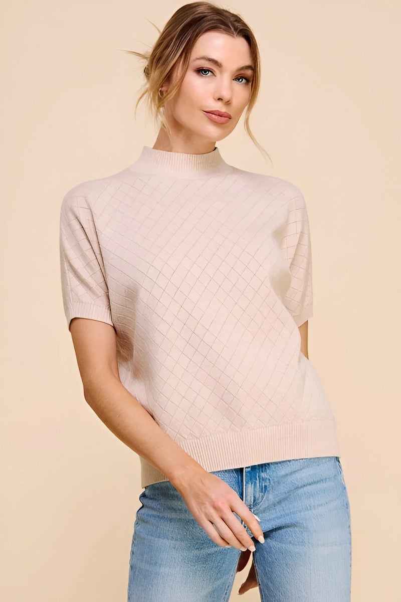 Woman in a soft short sleeve crosshatch mock neck top and blue jeans