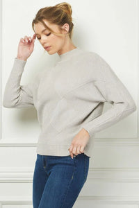 Woman modeling a soft long sleeve dolman mock neck sweater with blue jeans