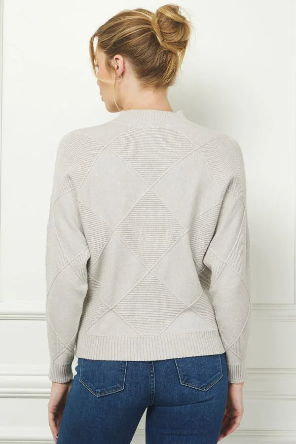 Woman in light gray soft long sleeve dolman mock neck sweater and blue jeans