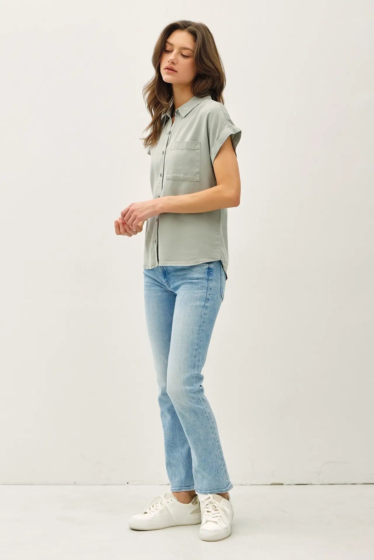Woman wearing a light green short dolman sleeve button down shirt with blue jeans
