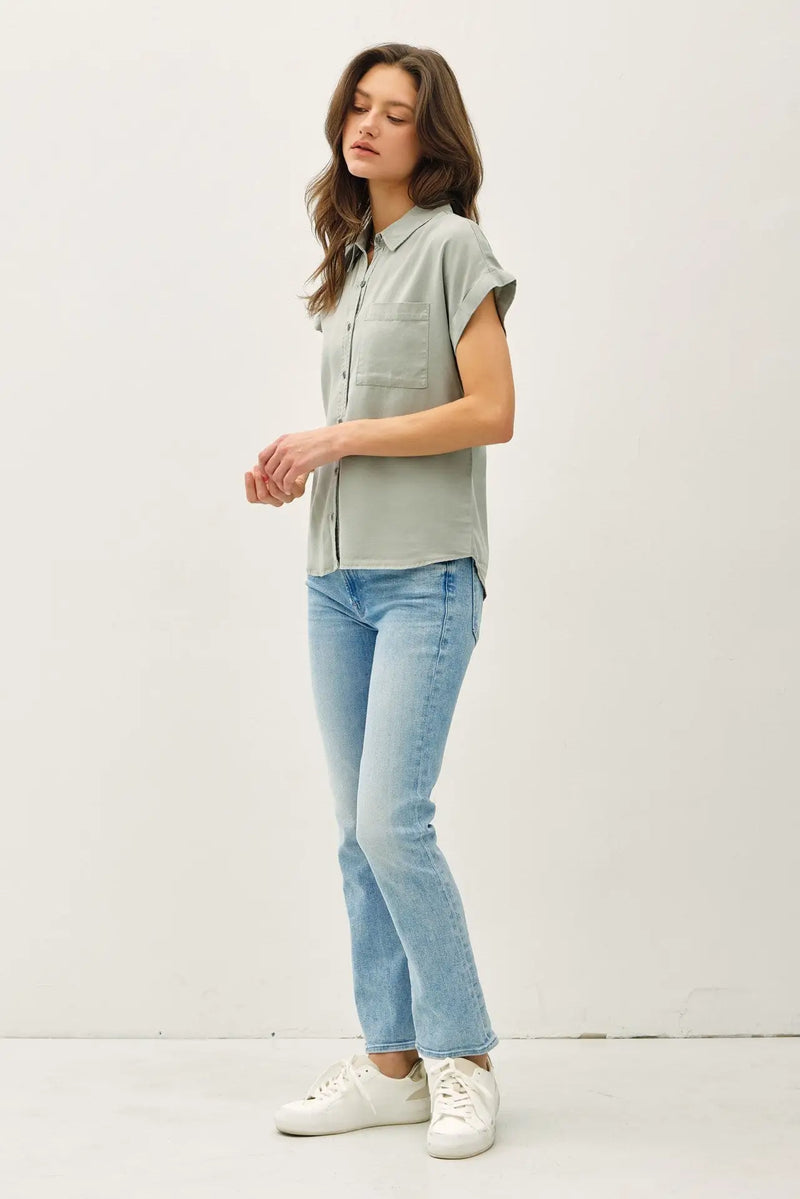 Woman wearing a light green short dolman sleeve button down shirt with blue jeans