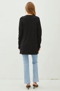 Woman in a long black knit sweater cardigan and light blue jeans from behind