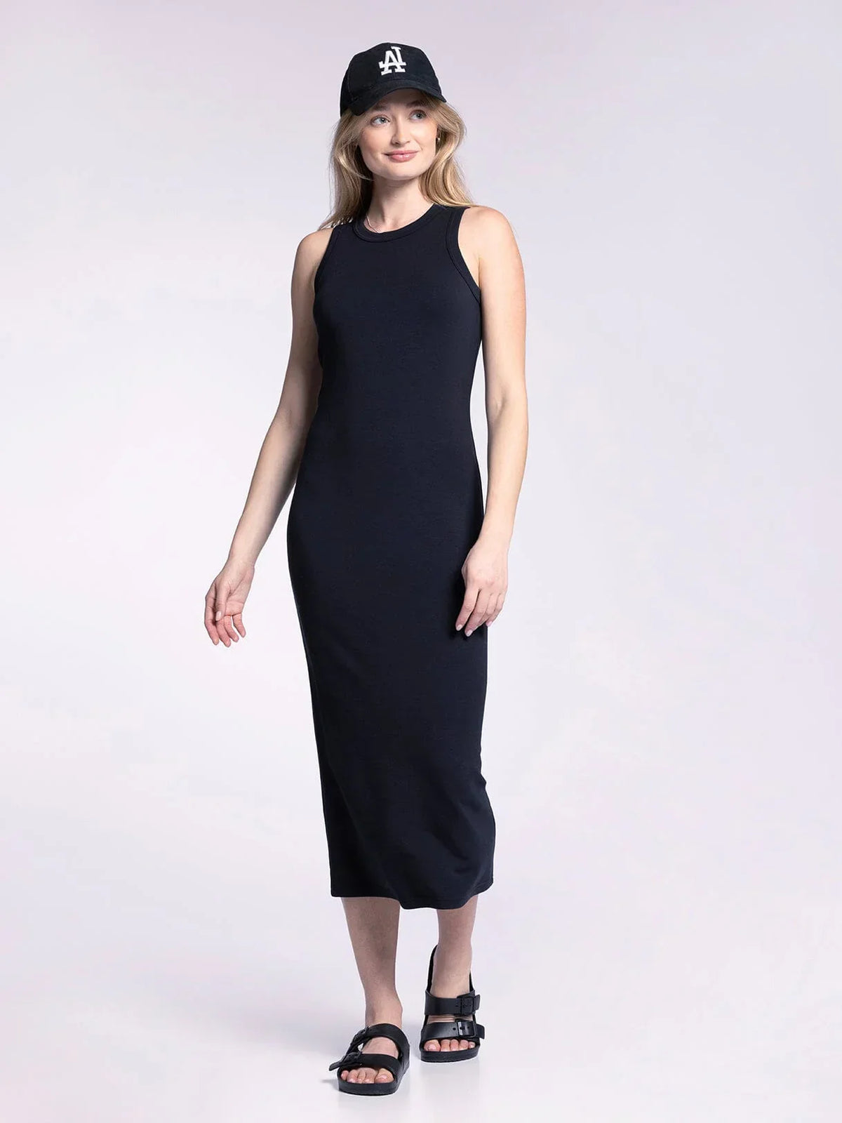 Woman in a long black tank fitted midi dress and baseball cap, showcasing stylish comfort