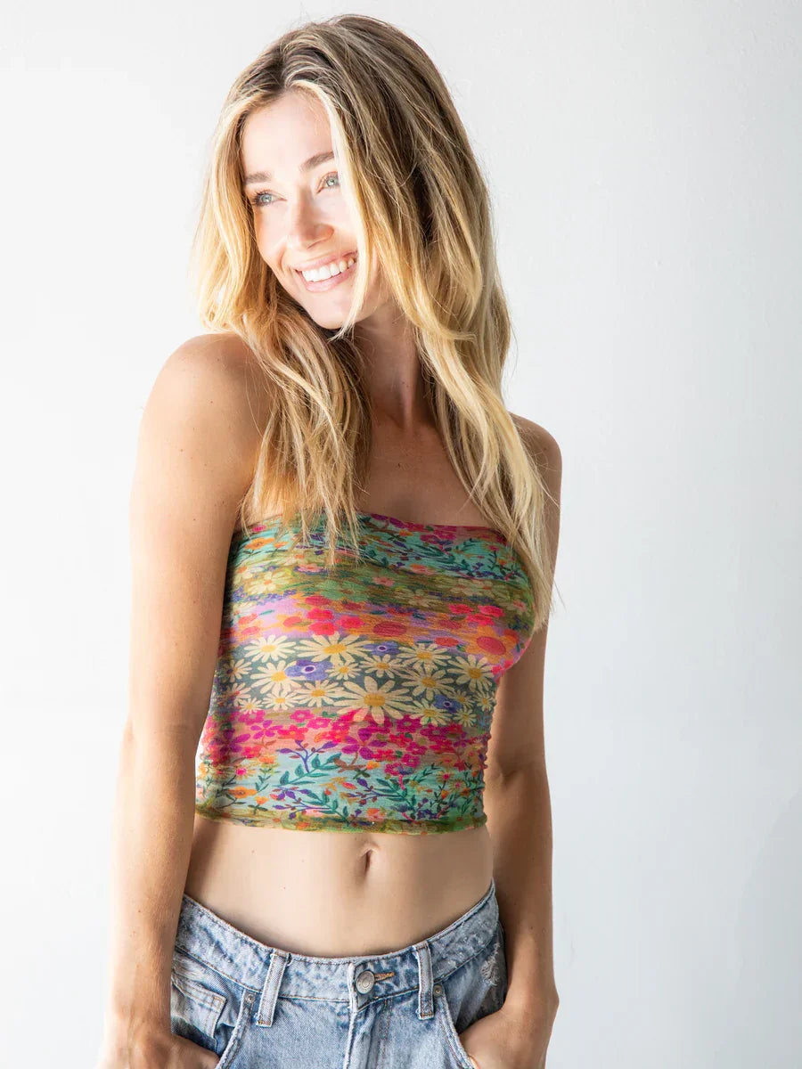 Smiling woman in colorful floral crop top and denim jeans showcasing Boho style with headband