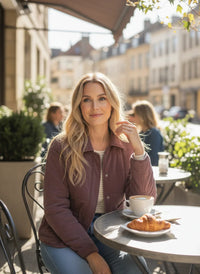 Woman wearing supply brina jacket and striped top at outdoor cafe with coffee and croissant