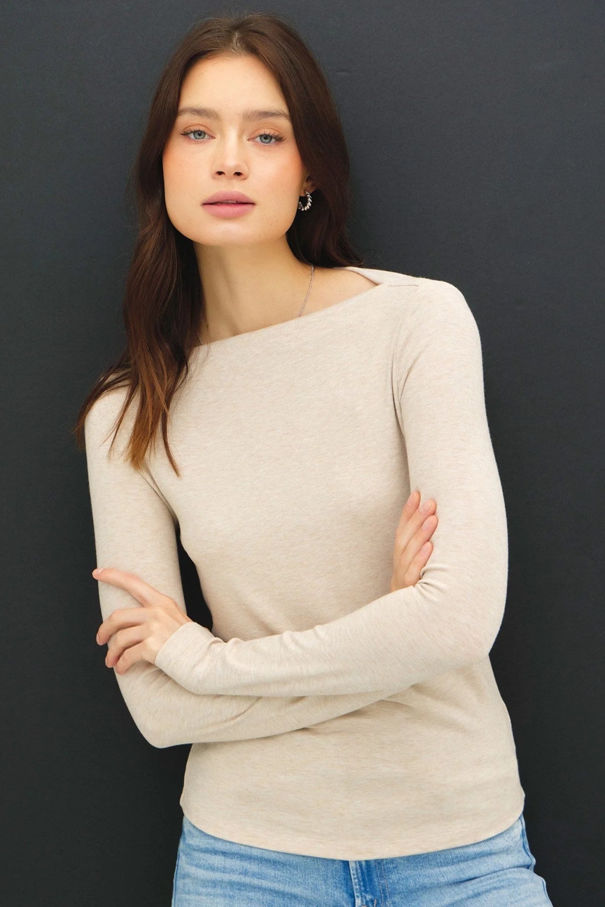 Woman wearing a basic boat neck long sleeve knit top with fitted silhouette and light-wash jeans