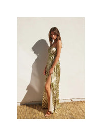 Woman in a green and white patterned halter neck maxi dress with a high slit