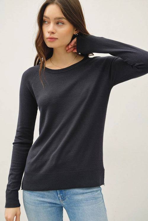 Woman modeling black round neck raglan long sleeve sweater with distressed hemlines for women’s boho chic clothing