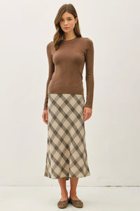 Woman wearing a basic patterned knit sweater with a beige and brown plaid midi skirt