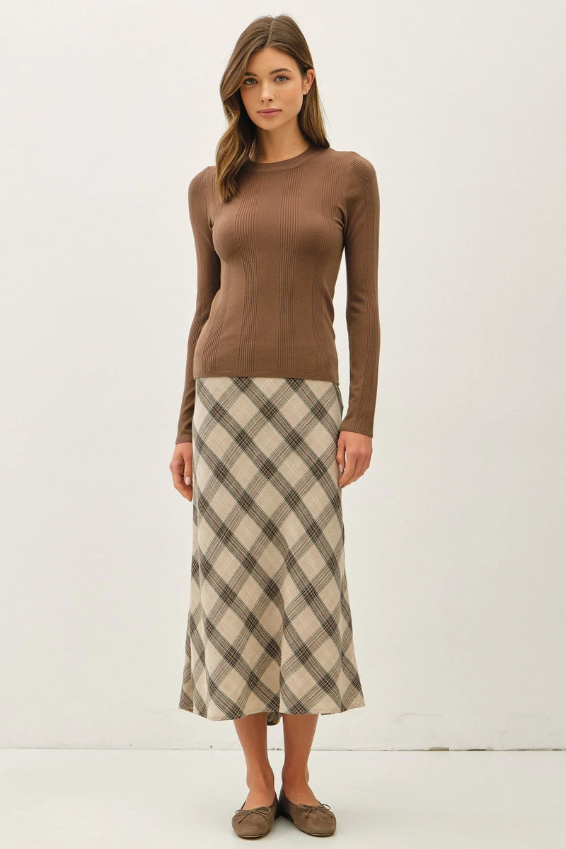 Woman wearing a basic patterned knit sweater with a beige and brown plaid midi skirt